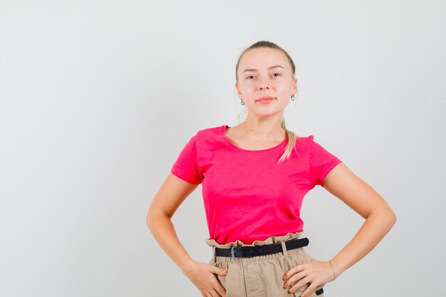 Mujer joven en camiseta y pantalón posando mientras está de pie y se ve hermosa