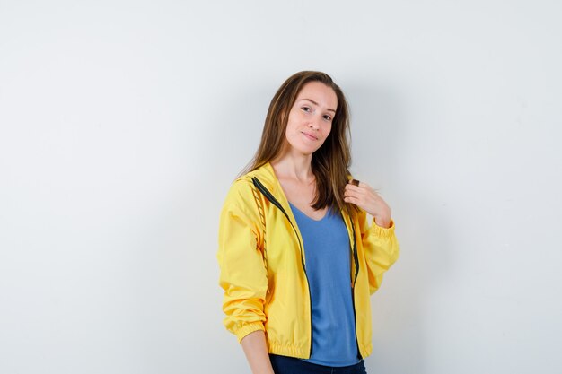 Mujer joven en camiseta posando mientras mira a la cámara y mira confiada, vista frontal.