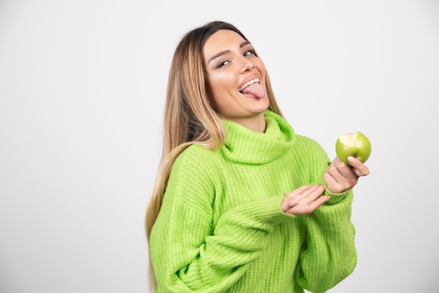 Foto gratuita mujer joven en camiseta verde sosteniendo una manzana.