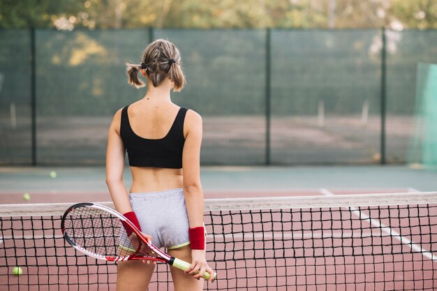 Mujer joven en el campo de tenis preparado para jugar