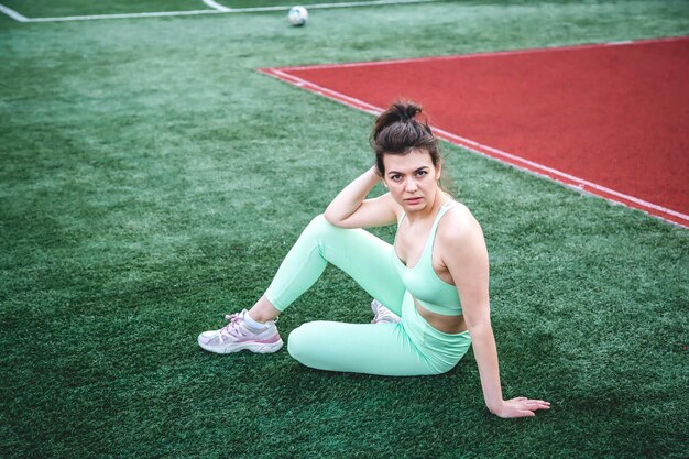 Mujer joven cansada en el estadio después de entrenar