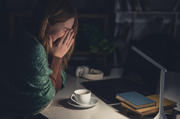 Foto gratuita mujer joven cansada en el lugar de trabajo quiere dormir hasta tarde en la noche