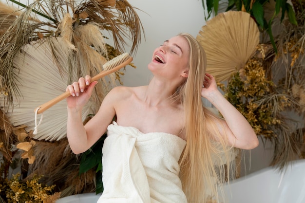 Foto gratuita mujer joven cantando mientras sostiene un cepillo para el cuerpo