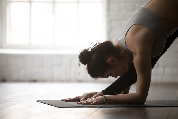 Mujer joven en una cara Fold pose, estudio blanco