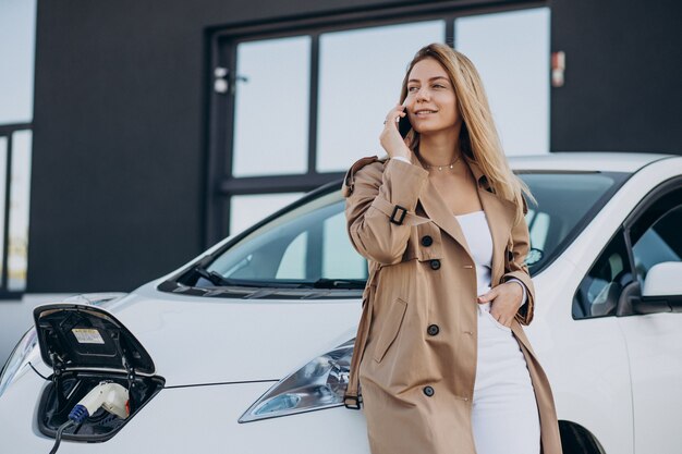 Mujer joven cargando su coche eléctrico con pistola de carga