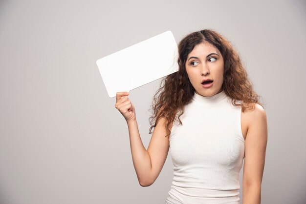 Foto gratuita mujer joven con cartel de discurso blanco en blanco vacío. foto de alta calidad