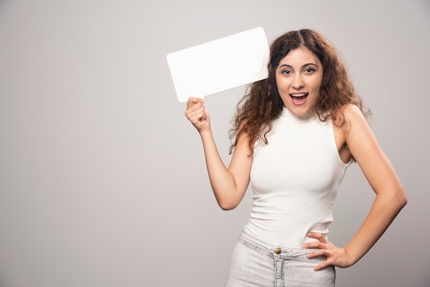 Mujer joven con cartel de discurso blanco en blanco vacío. Foto de alta calidad