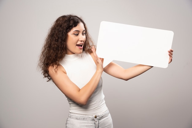 Mujer joven con cartel de discurso blanco en blanco vacío. Foto de alta calidad