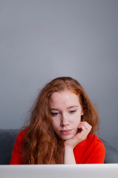 Foto gratuita mujer joven en casa leyendo en la computadora portátil