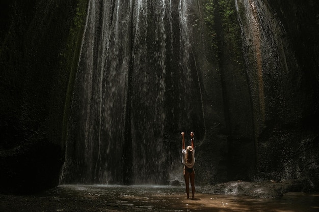 mujer joven en la cascada en la roca Bali Indonesia