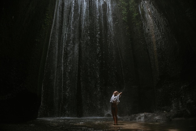 mujer joven en la cascada en la roca Bali Indonesia