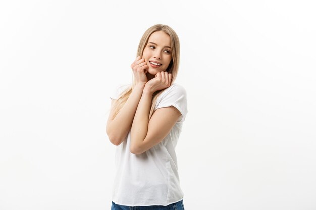 Mujer joven caucásica con linda sonrisa tímida juguetona adorable. Modelo camiseta blanca aislada sobre fondo blanco.