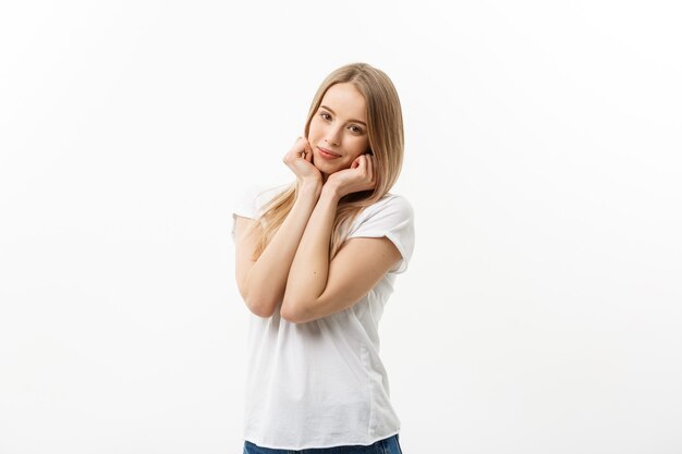 Mujer joven caucásica con linda sonrisa tímida juguetona adorable. Modelo camiseta blanca aislada sobre fondo blanco.