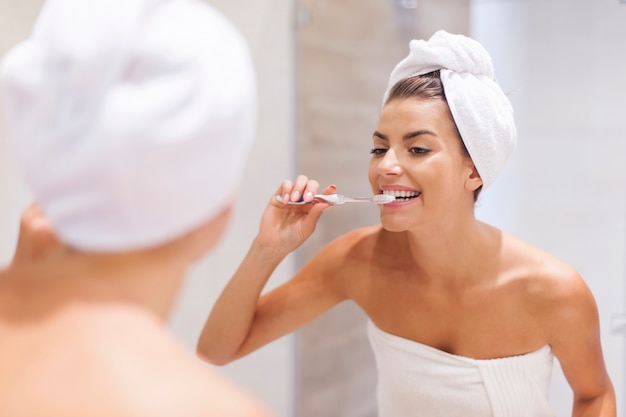 Mujer joven cepillarse los dientes en el baño.