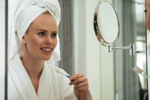 Foto gratuita mujer joven cepillarse los dientes contra el espejo