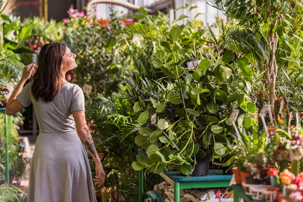 Mujer joven cerca de las plantas verdes en macetas