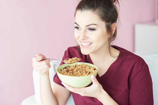 Mujer joven con cereales con leche para el desayuno