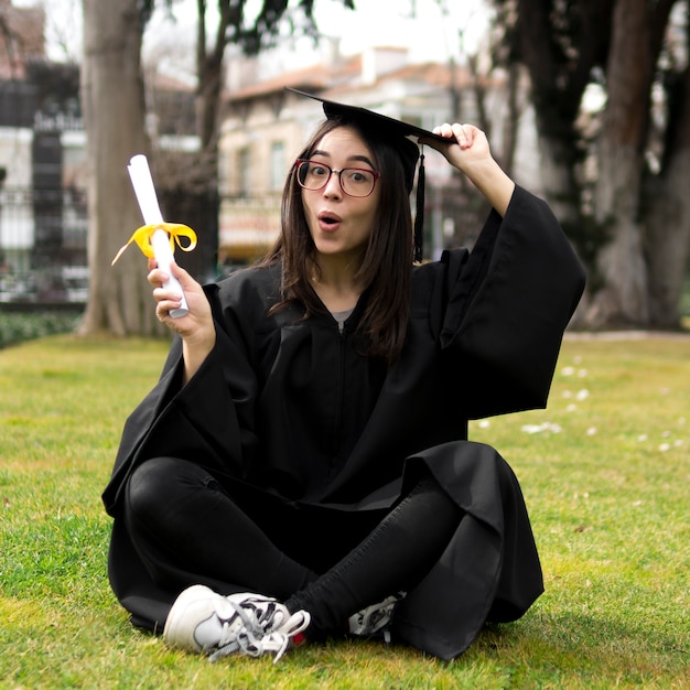 Mujer joven en la ceremonia de graduación sosteniendo su gorra