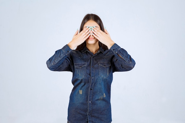 Foto gratuita mujer joven cerrando los ojos o parte de la cara y mirando a través de sus dedos