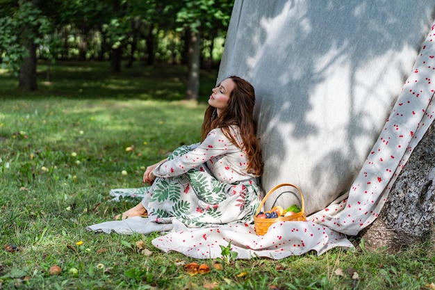 Mujer joven con una cesta de frutas, ciruelas y manzanas.