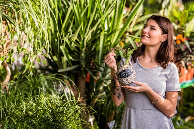 Mujer joven con cesta mirando plantas verdes