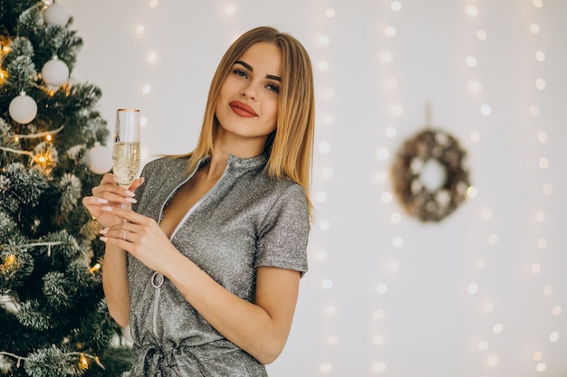 Foto gratuita mujer joven con champán por el árbol de navidad