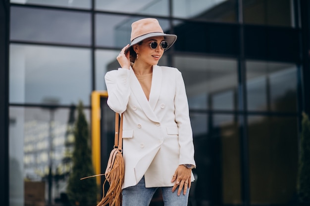 Mujer joven en chaqueta blanca caminando al aire libre