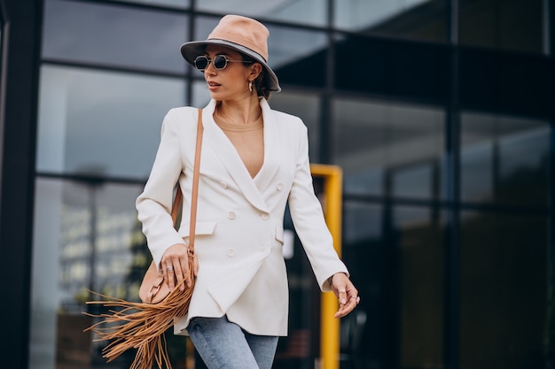 Mujer joven en chaqueta blanca caminando al aire libre