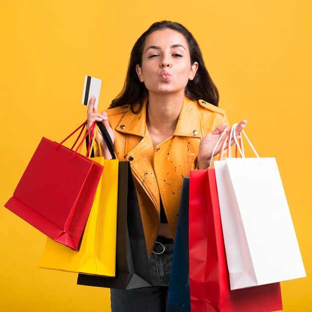 Mujer joven en chaqueta de cuero amarillo con bolsas de la compra.