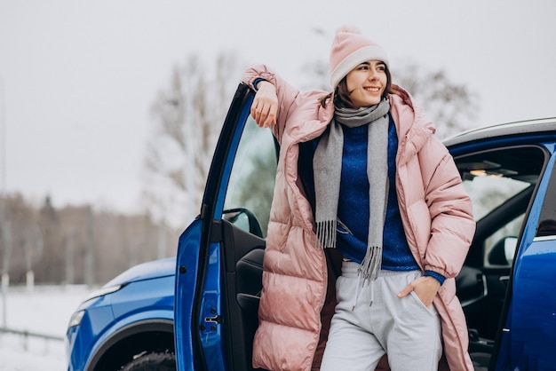 Mujer joven con chaqueta de invierno sentada en su coche nuevo