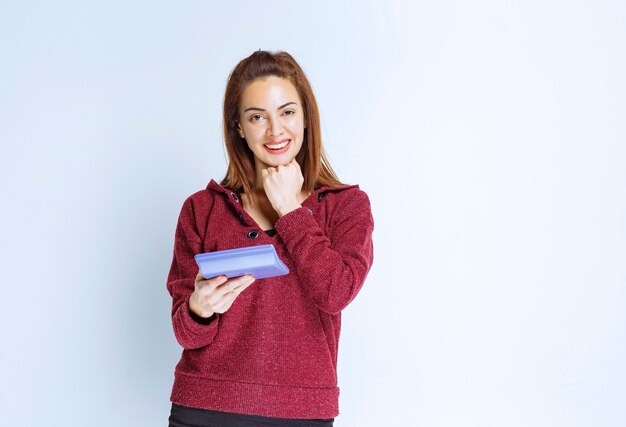 Mujer joven en chaqueta roja calculando algo en una calculadora azul y demostrando el resultado final