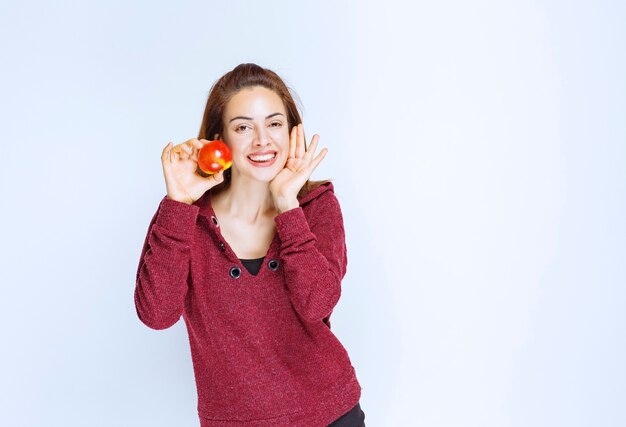 Mujer joven en chaqueta roja sosteniendo una manzana roja