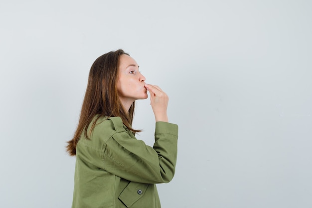 Mujer joven en chaqueta verde mostrando delicioso gesto.