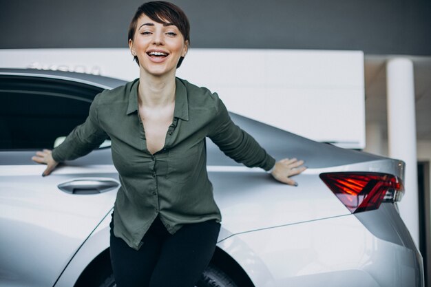 Mujer joven choosimng un coche en una sala de exposición de coches