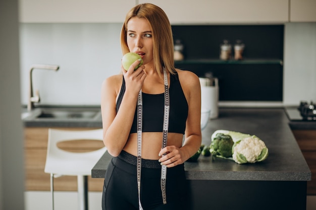 Mujer joven con cinta métrica en la cocina