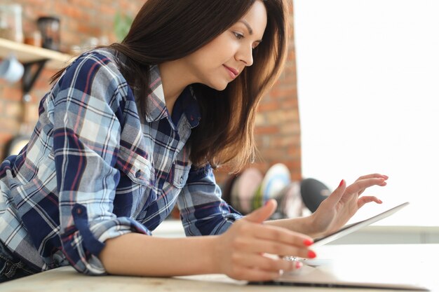 Mujer joven en la cocina con tableta digital.