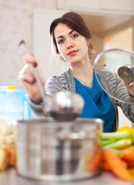 mujer joven cocinando sopa con laddle