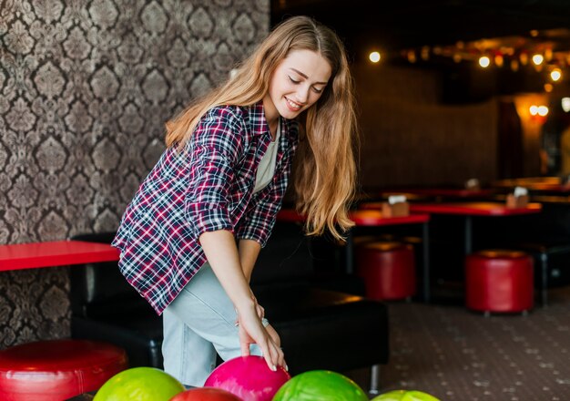 Mujer joven con coloridas bolas de boliche