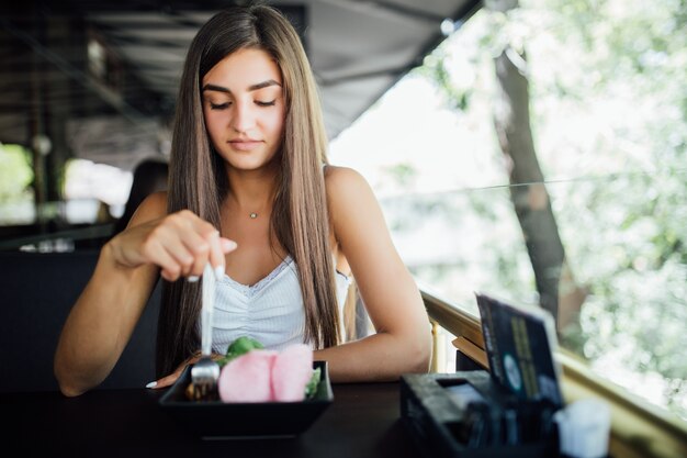 Mujer joven comiendo alimentos saludables sentado en el hermoso interior