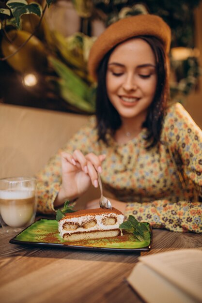 Mujer joven comiendo delicioso tiramisú en un café