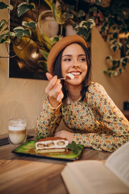 Mujer joven comiendo delicioso tiramisú en un café