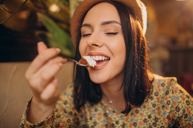 Mujer joven comiendo delicioso tiramisú en un café