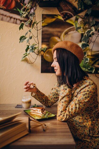 Mujer joven comiendo delicioso tiramisú en un café