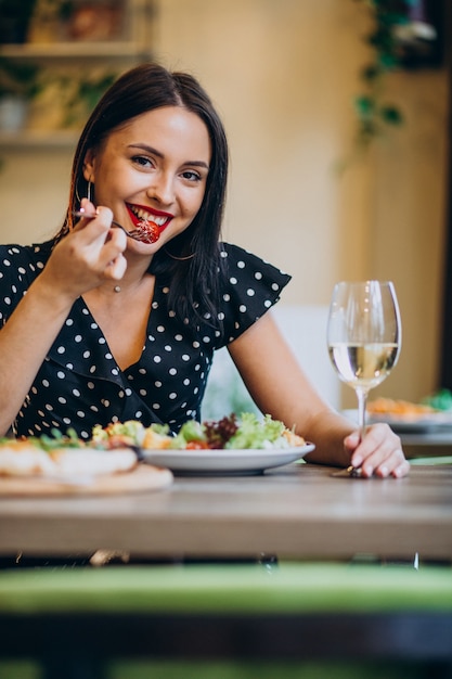 Mujer joven comiendo ensalada en un café