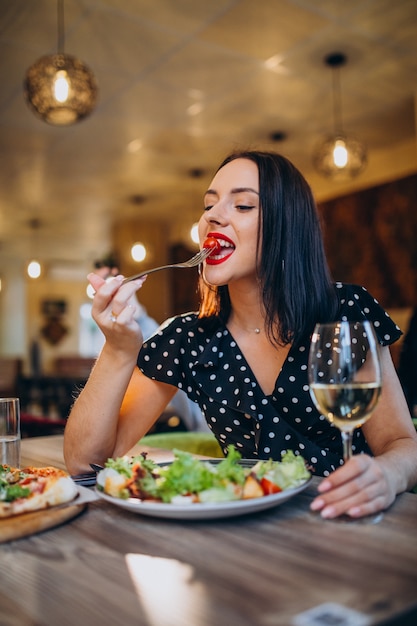 Foto gratuita mujer joven comiendo ensalada en un café