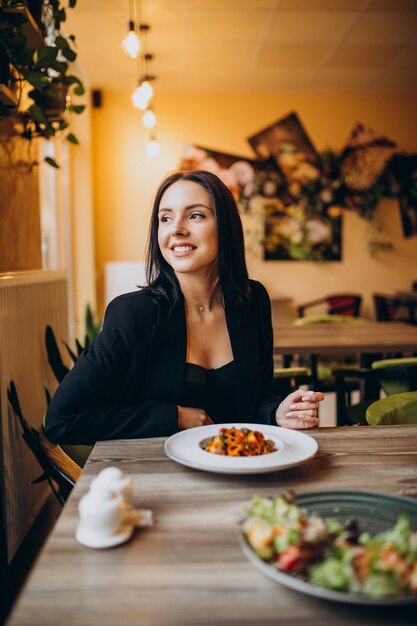 Mujer joven comiendo pasta en un café