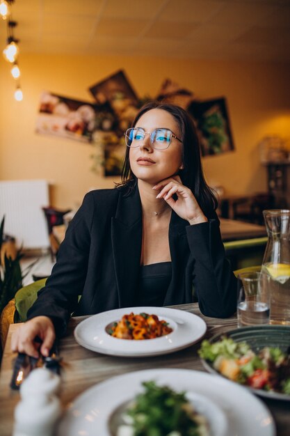 Mujer joven comiendo pasta en un café