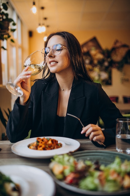 Mujer joven comiendo pasta en un café