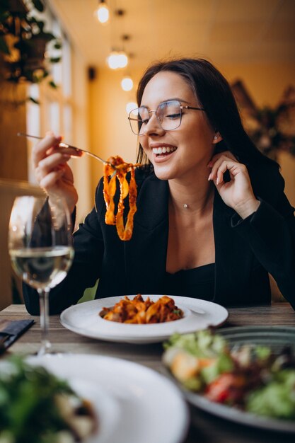 Mujer joven comiendo pasta en un café