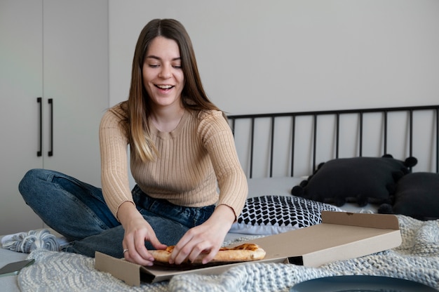 Foto gratuita mujer joven comiendo pizza en la cama